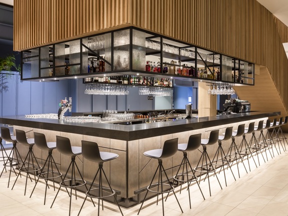 Modern hotel bar with black bar stools and wooden feature on ceiling