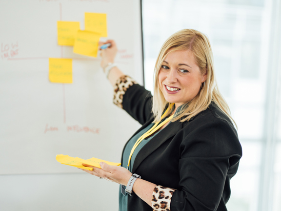 Woman placing post it notes on a whiteboard
