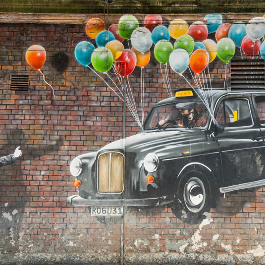 Mural of a man hailing a floating black cab, with colourful balloons tied to its wingmirrors