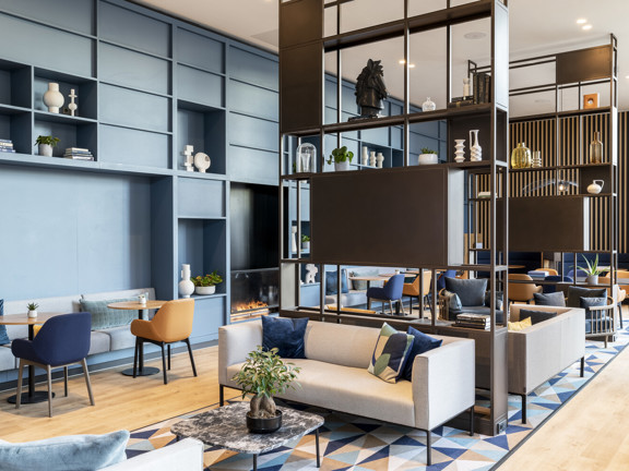 Modern hotel lobby with grey sofas and black display shelves. 