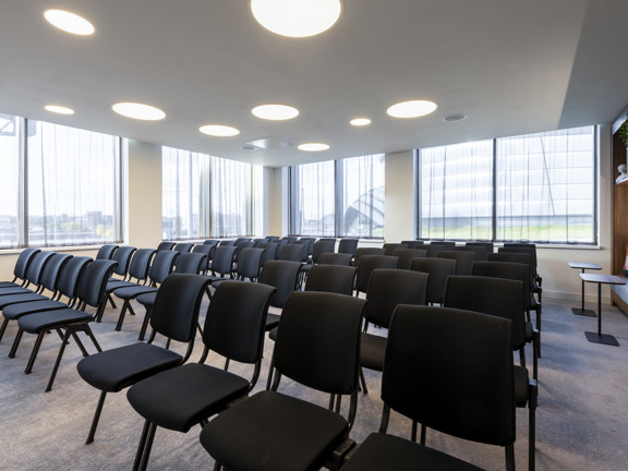 Meeting room with black chairs set up in rows. 