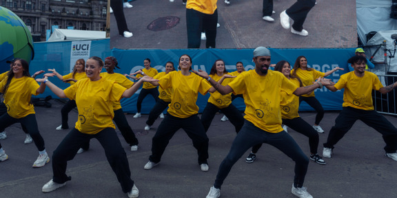 A group of young dancers wearing yellow t-shirts perform in George Square Glasgow during the 2023 UCI Cycling World Championships.