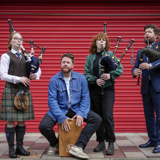 Four pipers standing infront of a red shutter