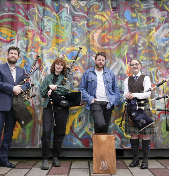 Four pipers standing infront of a colourful graffiti wall