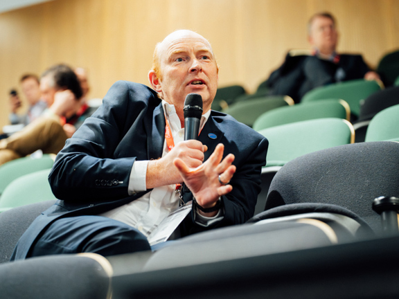 Conference delegate sitting on a chair asking a question into a microphone