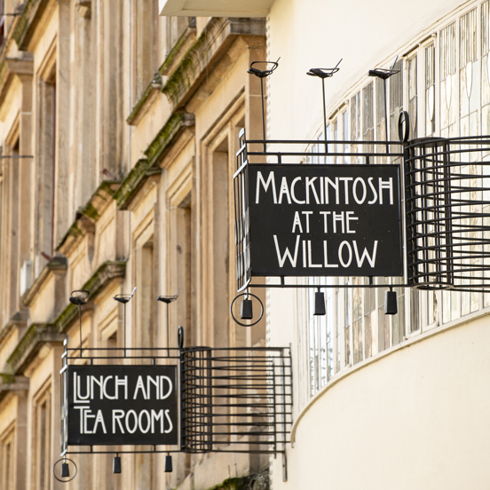 Exterior signs in the art-nouveau style of Charles Rennie Mackintosh reading Lunch and Tea Rooms and Mackintosh at the Willow