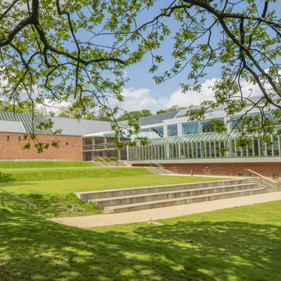 Glass and brick structure of The Burrell Collection through foliage