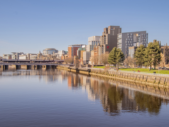 Sunny view of the River Clyde, with modern buildings on the bank, including the Virgin hotel