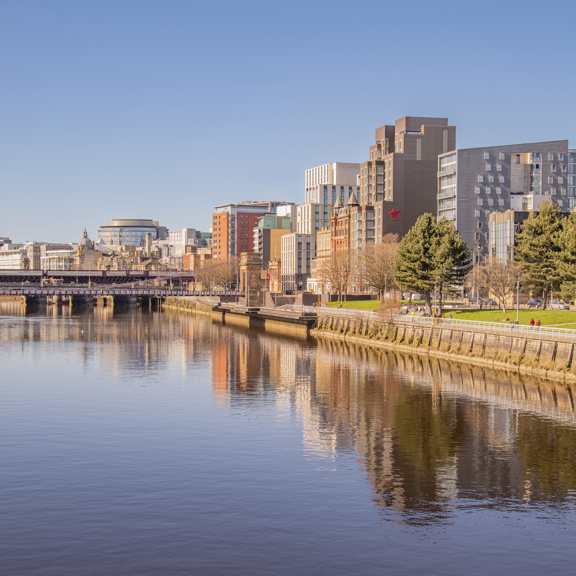 Sunny view of the River Clyde, with modern buildings on the bank, including the Virgin hotel