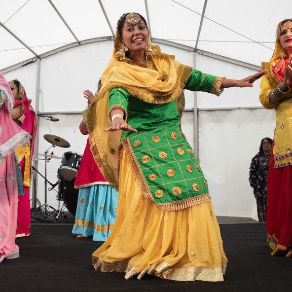 Five women perform on a covered stage in traditional Indian clothing.