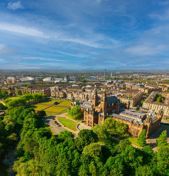 Glasgow cityscape, with the Baroque-style Kelvingrove Art Gallery and Museum, surrounded by greenery. The modern buildings of the Scottish Event Campus and the Glasgow Science Centre are visible in the background